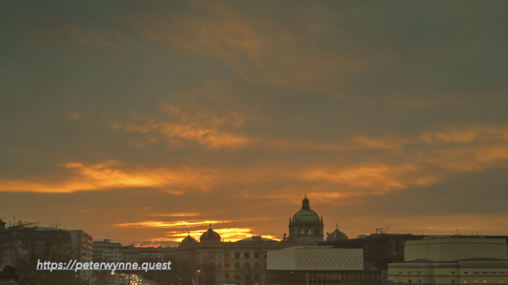 Prague skyline at sunset with dome in the distance by Peter Wynne