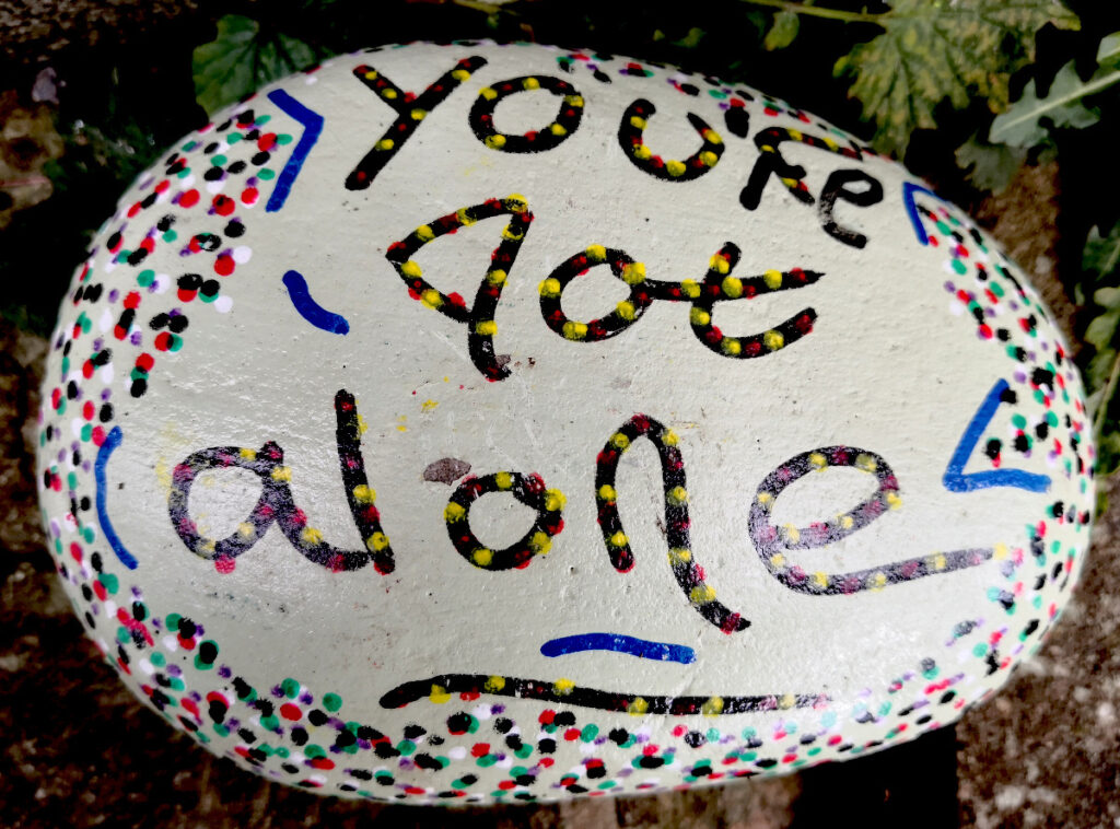 painted stone with the inscription: - 'you're not alone'